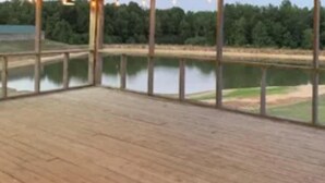 Una terraza de madera con vistas a un lago y árboles.