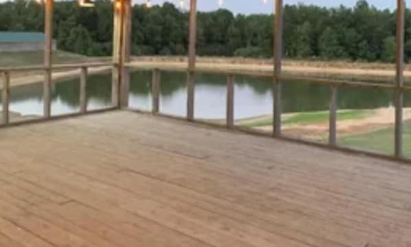 Um deck de madeira com vista para um lago e árvores.