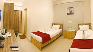 A hotel room with two beds, a desk with a kettle, a TV, and a small table with a kettle and remote controls. - Corporate Stays (Chengalpattu)