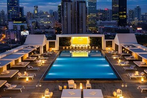 Una piscina sul tetto con lettini e lo skyline della città sullo sfondo.