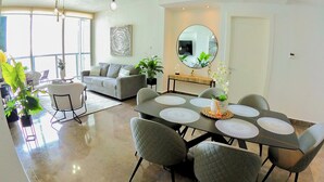 Un salon moderne comprenant un coin repas, un canapé, une table basse et une grande fenêtre.