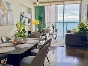 Ein modernes Wohnzimmer mit Essbereich, großen Fenstern und Meerblick.