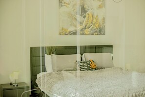 A bedroom with a round bed, a green headboard, and a painting on the wall. - Modern Ocean View Apartment in Av. Balboa King Bed, Pool & Gym (Panamá)
