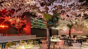 Un restaurant avec des tables et des chaises rondes, et un panneau lumineux au néon.