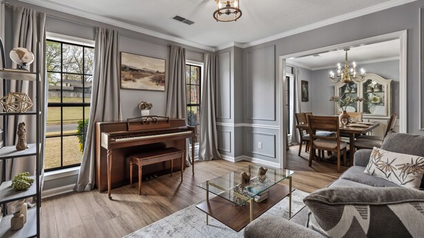 Ein Wohnzimmer mit einem Klavier, einem Glastisch und einer Couch.