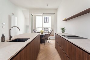 Una cocina moderna con dos fregaderos, un comedor con mesa y sillas, y vistas al exterior.