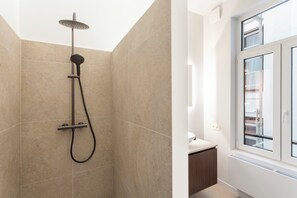 Un baño moderno con ducha, ventana y lavabo.