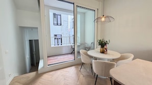 Eine moderne Wohnung mit Balkon, einem Essbereich inklusive Tisch und Stühlen sowie einer Pendelleuchte.