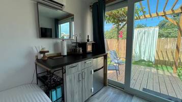 Una cocina moderna con un amplio ventanal, puerta corrediza a una terraza y un pequeño comedor.
