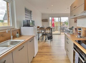 A modern kitchen with a wooden countertop, stainless steel sink, and a dining area with a table and chairs. - Ker Koad - PLOURIVO - Gîte (PLOURIVO)