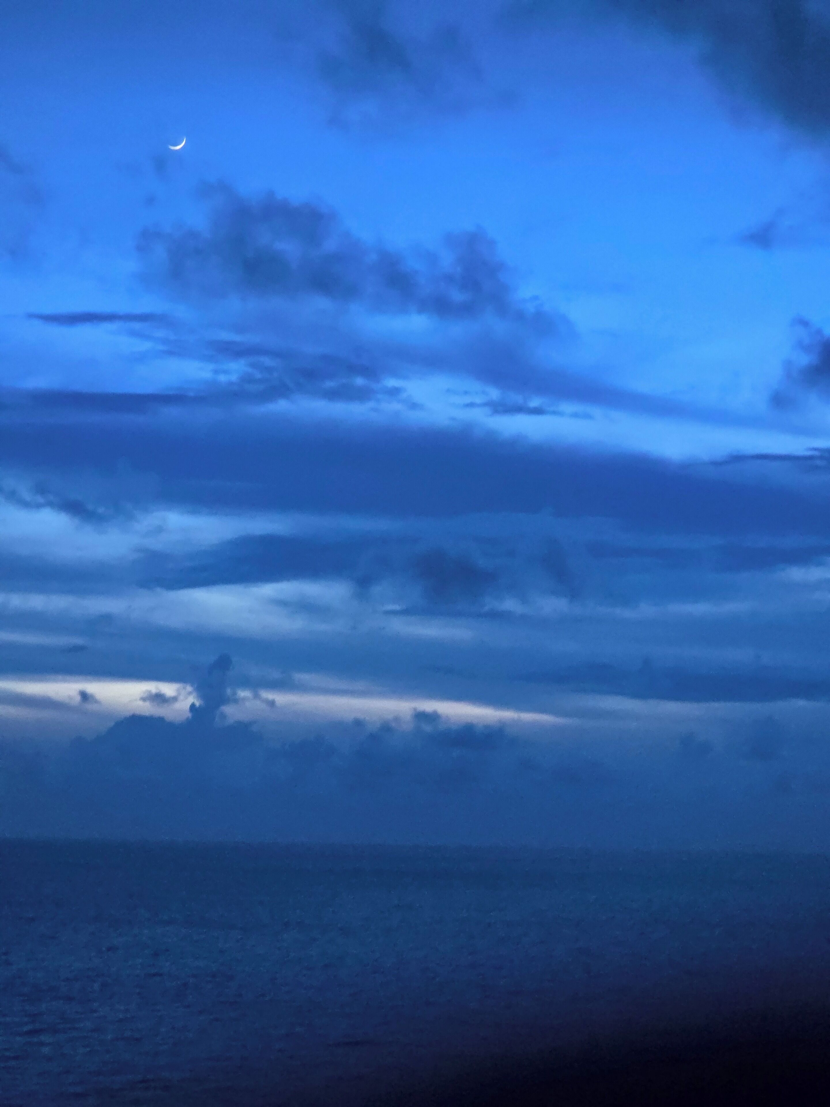 A night sky with clouds and a crescent moon.