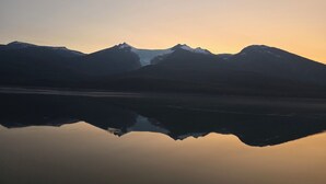 Et bjerglandskab genspejlet i stille vand ved solopgang eller solnedgang.