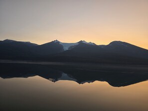 A mountain range reflected in a calm body of water during sunrise or sunset. - Spacious 4-bedroom house with AC in amazing Brevard CONNESTEE FALLS (Brevard)
