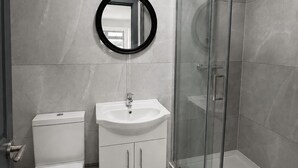 Et moderne badeværelse med toilet, vask og brusekabine i glas.