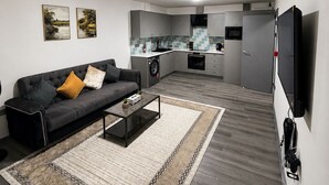 En moderne stue med sofa, sofabord og et billede på væggen.