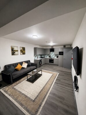 En moderne stue med sofa, sofabord og et billede på væggen.