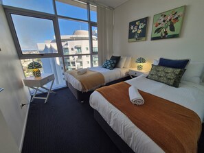 A hotel room with two beds, a desk, and a large window offering a city view. - The Gilded Gallery I Art-Inspired Luxe (Brisbane City)