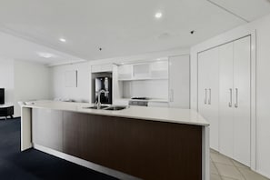 Una cocina moderna con una isla central, electrodomésticos integrados y armarios blancos.