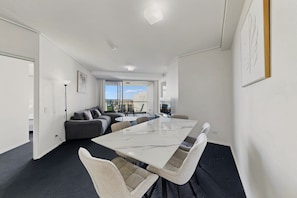 Una sala moderna con un sofá, una mesa de comedor y vistas a la ciudad.