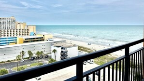 Hotel aan het strand met uitzicht op de oceaan, een parkeerplaats en een weg.