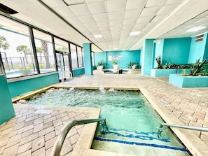 Ein Innenpool mit Fliesenboden, einer zentralen Wasserspüle und Topfpflanzen.