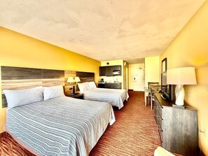 A hotel room with two beds, a desk with a lamp, a television, and a minibar. - Salty Vibes Sleeps 4 315 (Myrtle Beach)
