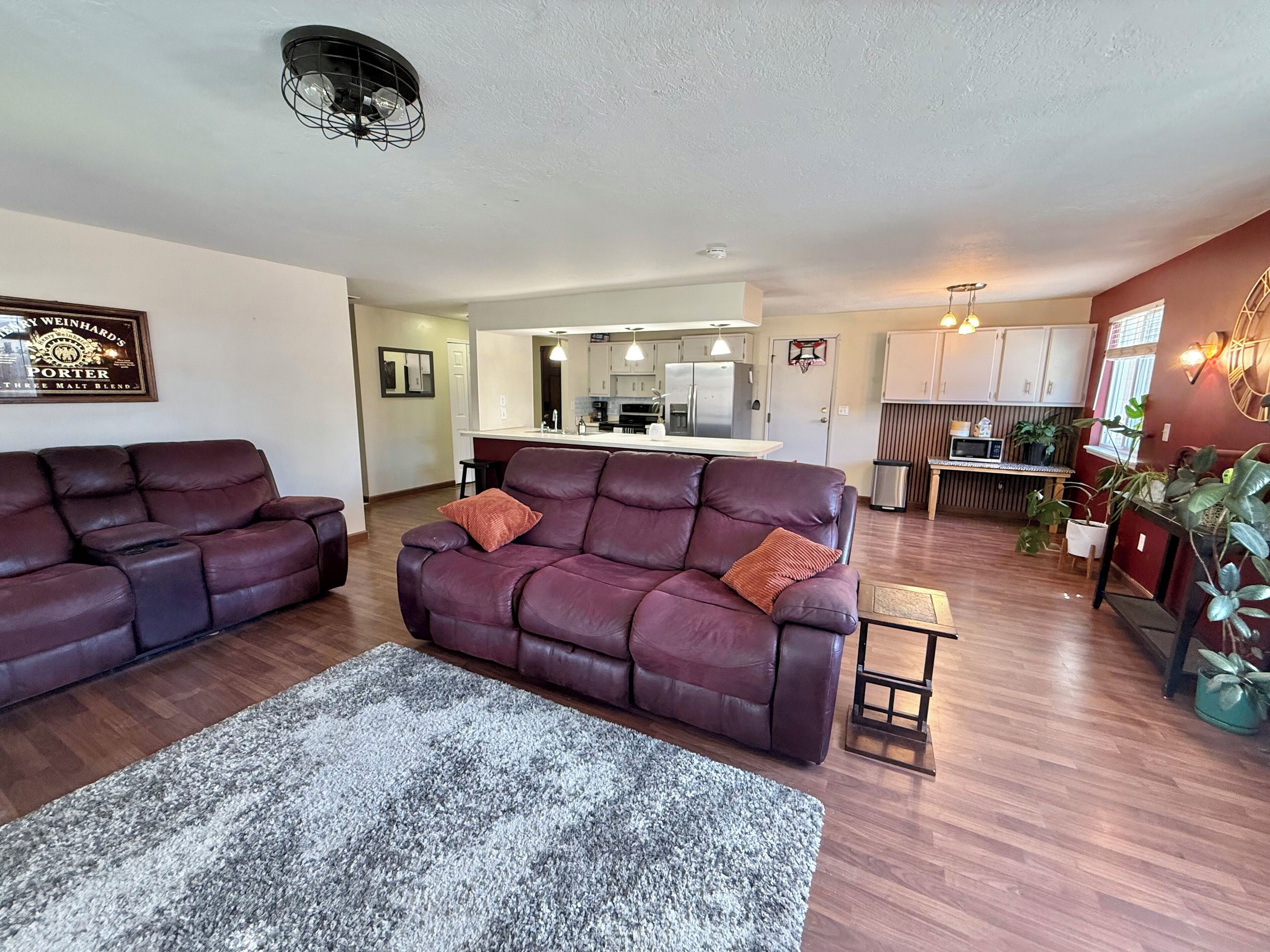 A living room with two leather sofas, a grey rug, and a kitchen in the background.