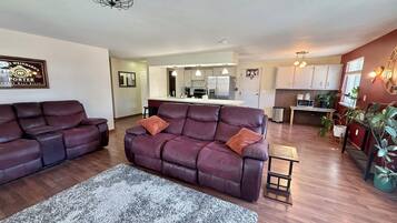 A living room with two leather sofas, a grey rug, and a kitchen in the background.