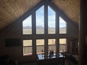Una habitación con techo alto y ventanas amplias que ofrecen vista a un paisaje desértico.