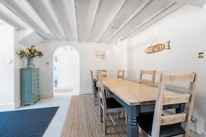 A dining area with a wooden table and chairs, a vase with flowers, and a 'BEACH' sign on the wall.