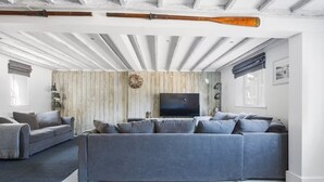 Ein modernes Wohnzimmer mit einem großen grauen Sofa, einem Fernseher und einer Holzwandverkleidung.