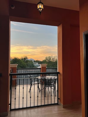 A balcony with a table and chairs, a view of the sky, and a railing.