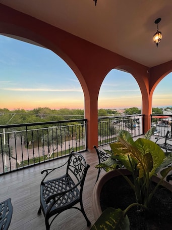 A balcony with a view of the sunset, a potted plant, and a metal chair.. Hotel Las Carolinas
