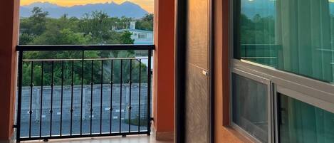 A balcony with a view of mountains and a sunset.