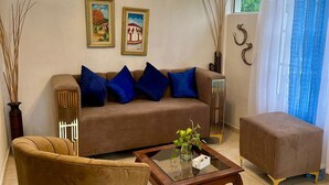 Ein Wohnzimmer mit Sofa, Sessel, Couchtisch, Deckenventilator und einem Kunstwerk an der Wand.