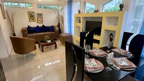 Ein Wohnzimmer mit einer Couch, einem Couchtisch und einem Essbereich mit Tisch für vier Personen.