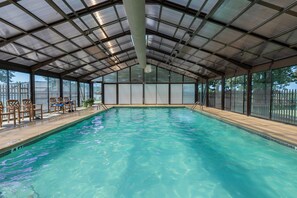 Ein überdachter Pool mit Metalldach, Holzstühlen und Blick ins Freie.