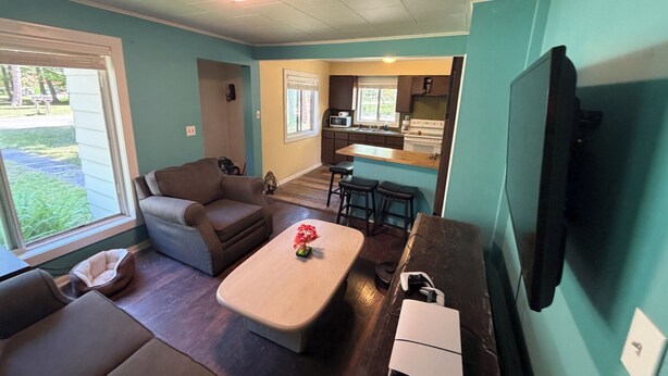 Un espacio habitable pequeño con un sofá, una mesa de centro, un televisor y una zona de kitchenette.