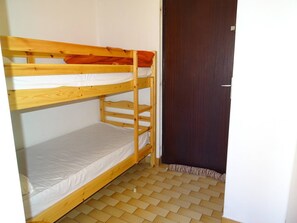 Ein Stockbett mit einer unteren Liege und einer Tür rechts.