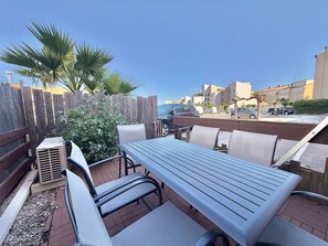 Eine Terrasse im Freien mit Tisch und Stühlen, einem Holzzaun und einem parkenden Auto.