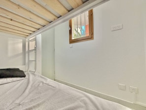Ein Schlafzimmer mit einem Bett, einem Fenster und einer Holzbalkendecke.