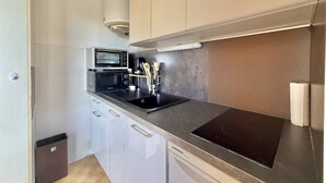 A compact kitchen with a microwave, stove, and sink. - CAP D'AGDE - Plage du Môle / Réf 0101 (CAP D'AGDE)