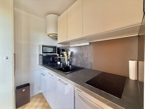 A compact kitchen with a microwave, stove, and sink. - CAP D'AGDE - Plage du Môle / Réf 0101 (CAP D'AGDE)