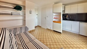 A compact living space with a sofa, a kitchenette, and a door leading to another room. - CAP D'AGDE - Plage du Môle / Réf 0101 (CAP D'AGDE)