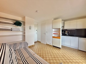 A compact living space with a sofa, a kitchenette, and a door leading to another room. - CAP D'AGDE - Plage du Môle / Réf 0101 (CAP D'AGDE)