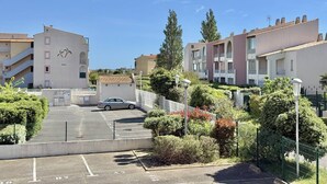 Ein Wohngebiet mit Mehrfamilienhäusern, einem Parkplatz und Grünflächen.