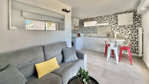 Ein modernes Wohnzimmer mit einem grauen Sofa, einem Couchtisch mit einer Pflanze und einem Essbereich mit roten Stühlen.