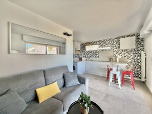 Ein modernes Wohnzimmer mit einem grauen Sofa, einem Couchtisch mit einer Pflanze und einem Essbereich mit roten Stühlen.