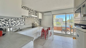 Eine moderne Küche mit Einbaugeschirrspüler, einem großen Fenster und einem Balkon mit roten Stühlen.