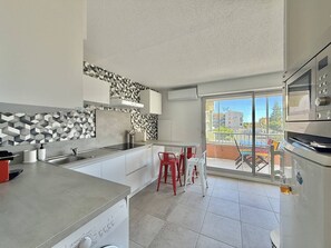 Eine moderne Küche mit Einbaugeschirrspüler, einem großen Fenster und einem Balkon mit roten Stühlen.